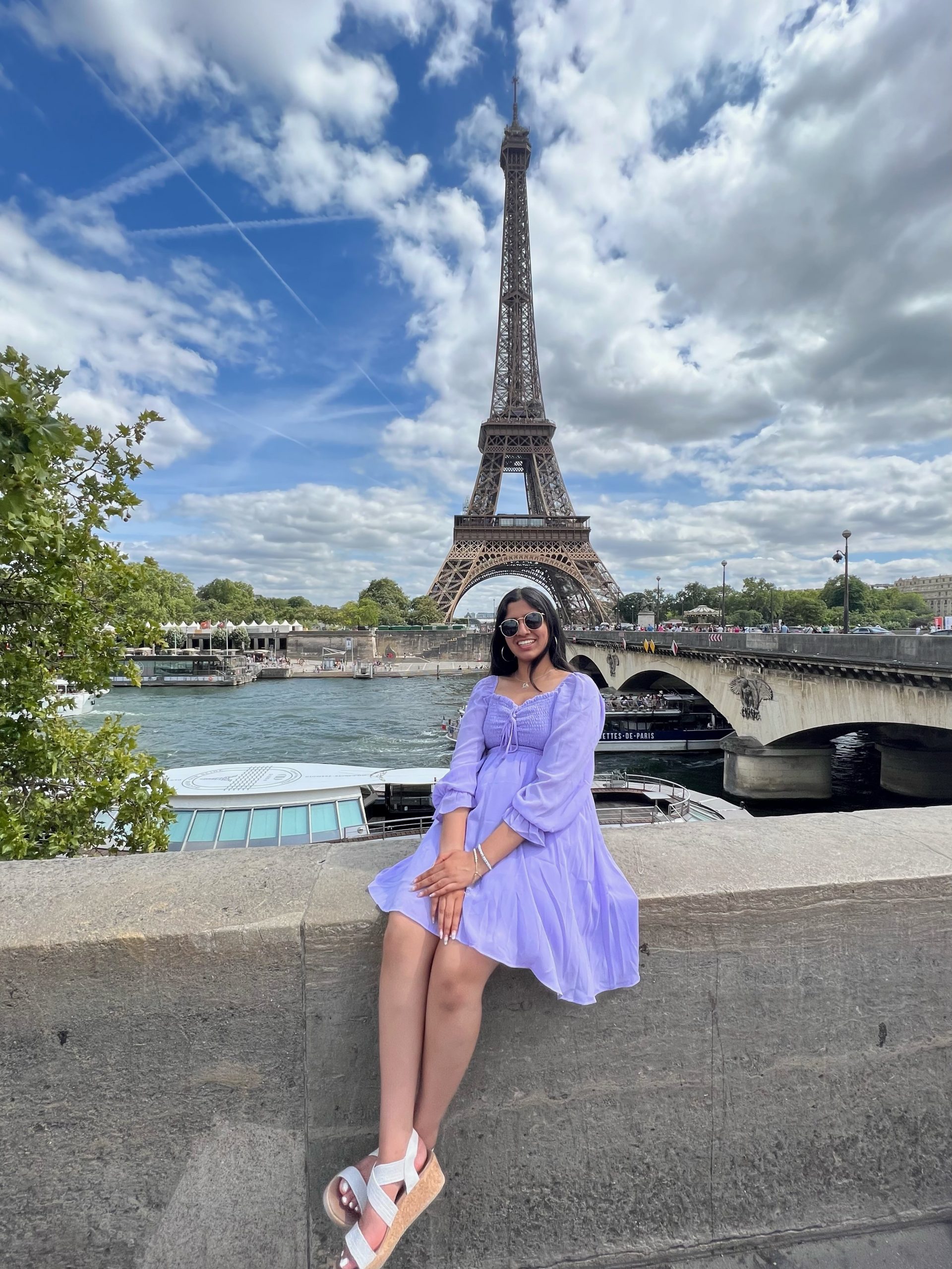 Aditi Malpure, Stamps Scholar, individual photo sitting on wall near Eiffel Tower in Paris, France. 